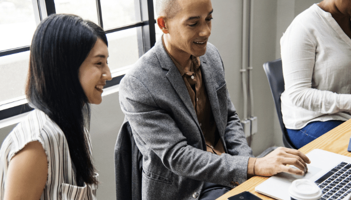 two people sitting next to each other on a computer