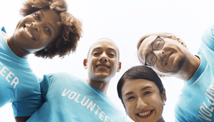 four people wearing t-shirts that say "volunteer"